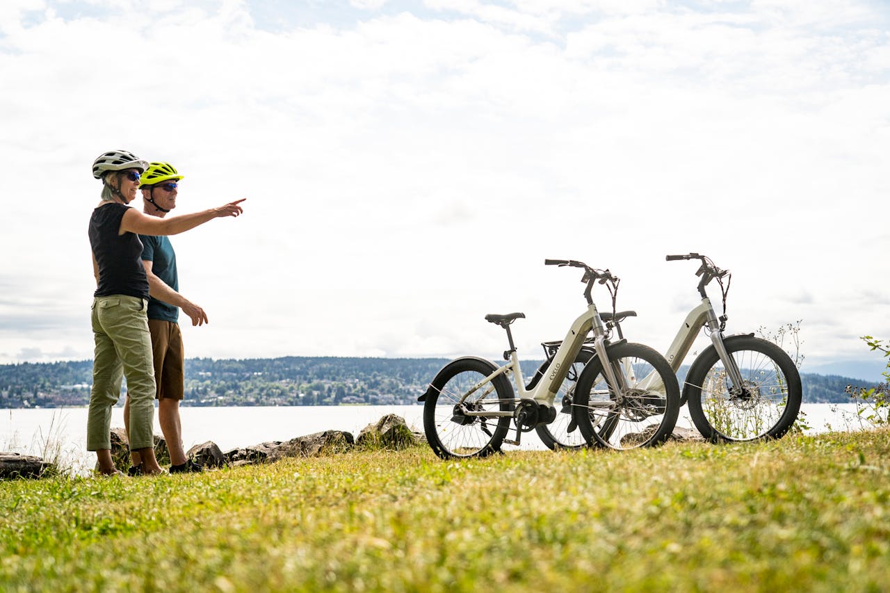 A couple in helmets points while enjoying an electric bike adventure near Seattles scenic waterfront.
